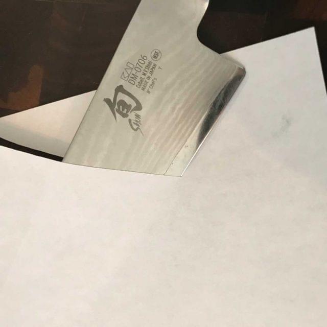 A knife slicing through a sheet of paper.