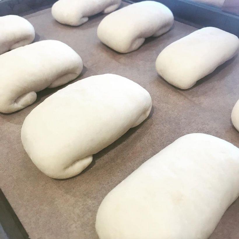 Two rows of pale, raised, envelope-folded packets of dough on a parchment-lined baking sheet.