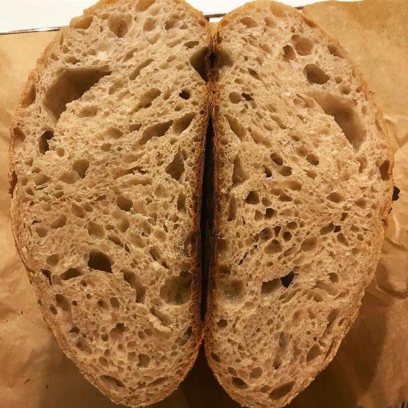 A cross-section of a sourdough boule with an open, irregular crumb structure.