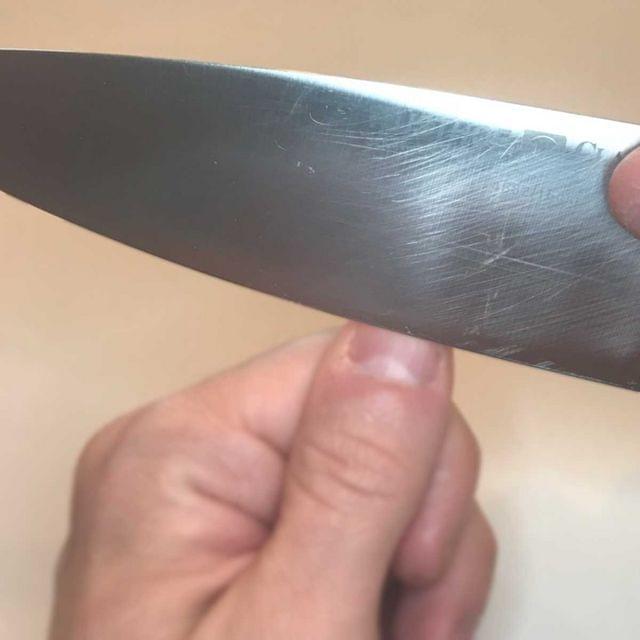 A knife held at a steep angle against the photo-taker’s thumbnail.