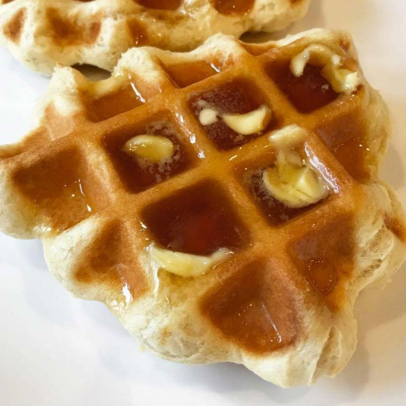 A thick, triangular, golden brown waffle with butter and syrup.